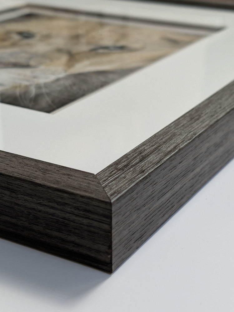 Close-up of a wooden picture frame with a blurred artwork inside.