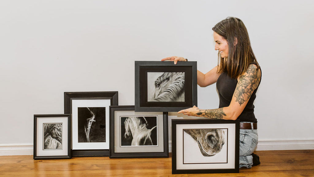 Artist holding a collection of horse artwork