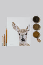 Artwork of a deer face with pastel supplies on a light gray background