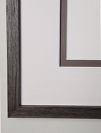 Close-up of a dark wooden frame with chalk white outer matting and brown/grey inner matting