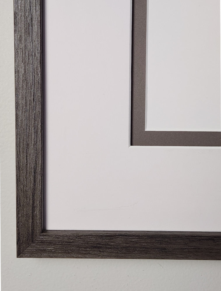 Close-up of a dark wooden frame with chalk white outer matting and brown/grey inner matting