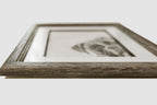 Framed black and white pastel drawing on a light gray background