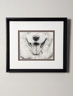 Framed black and white portrait of a dog smile drawn in pastels on a light gray wall