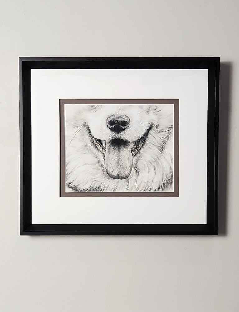 Framed black and white portrait of a dog smile drawn in pastels on a light gray wall