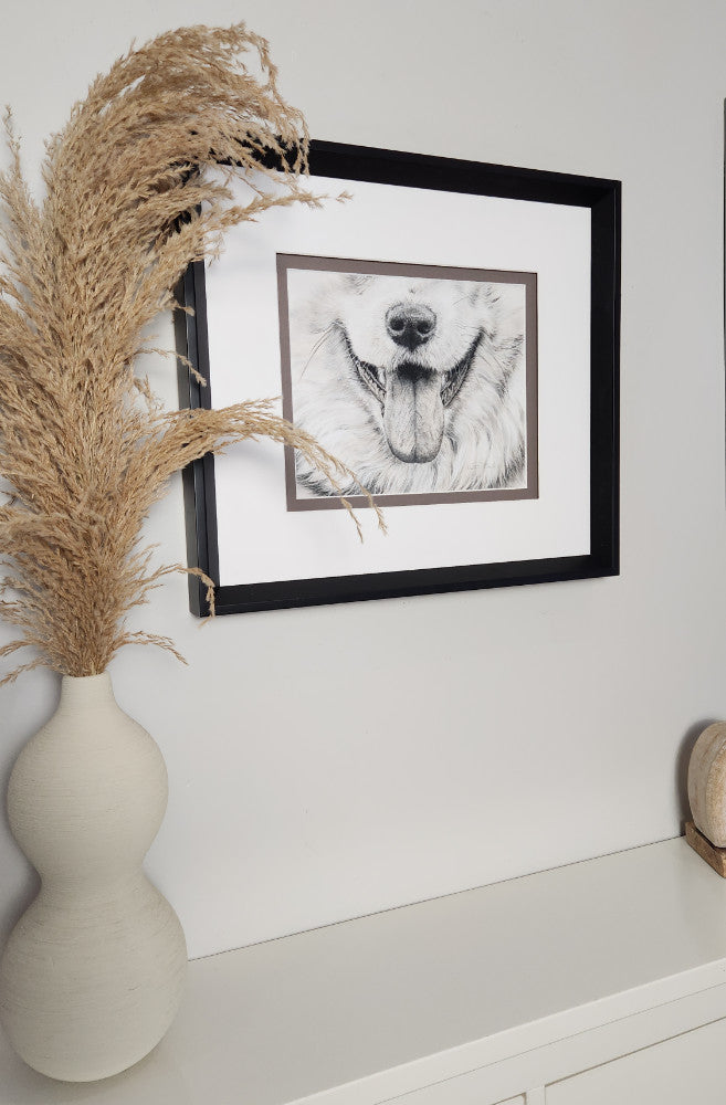 Framed artwork of a dog's face on a white wall with decorative elements.