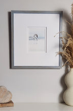 Framed artwork of a swan on a white wall with a vase and decorative object in the foreground.