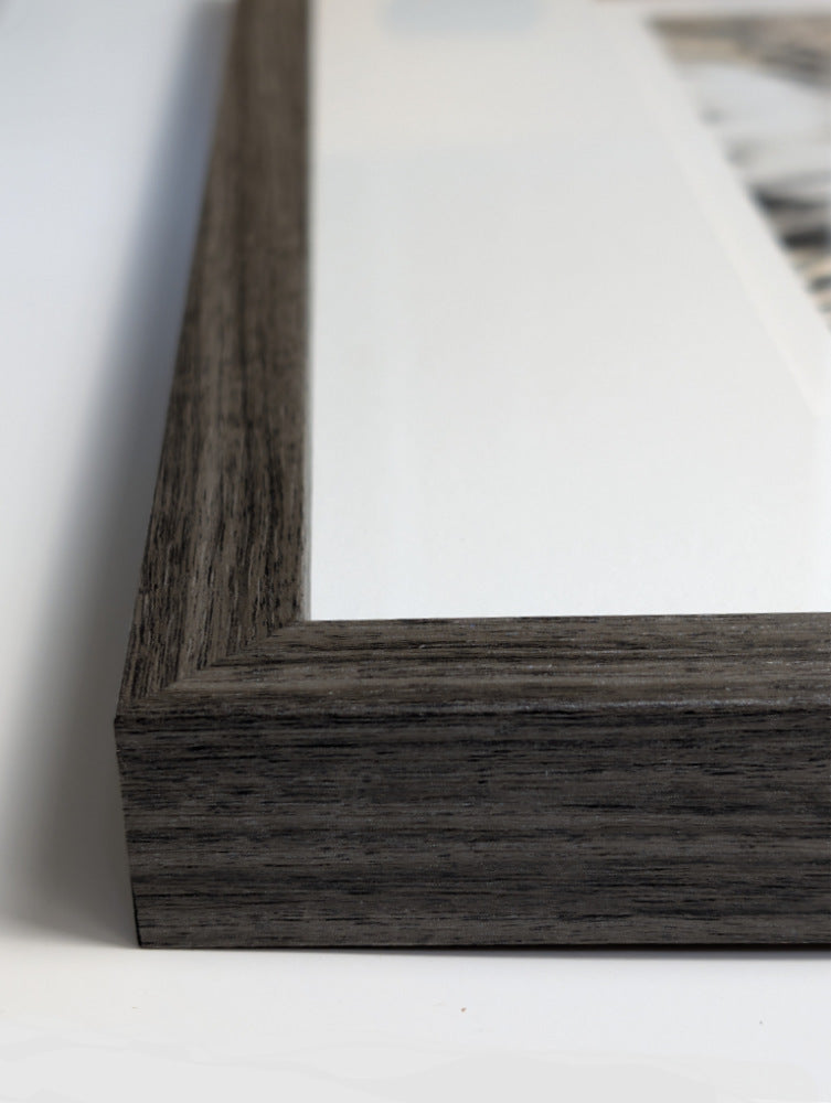 Close-up of a dark wooden picture frame on a white surface
