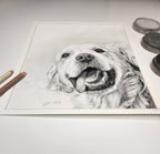 Pastel drawing of a dog on a white surface with art supplies.