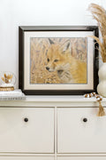 Framed artwork of a fox on a shelf with decorative items.