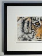Framed artwork of a tiger's face on a white wall