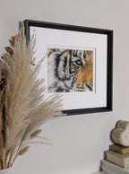 Framed artwork of a tiger's face on a wall with decorative elements.
