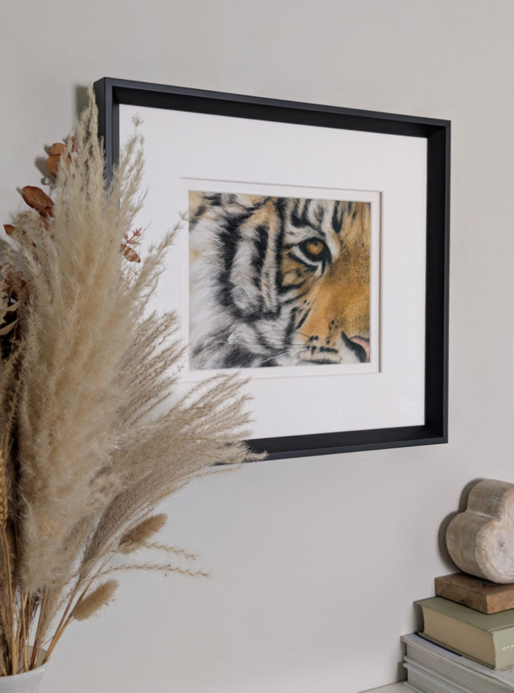Framed artwork of a tiger's face on a wall with decorative elements.