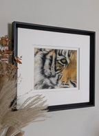 Framed artwork of a tiger's face on a wall with decorative elements.