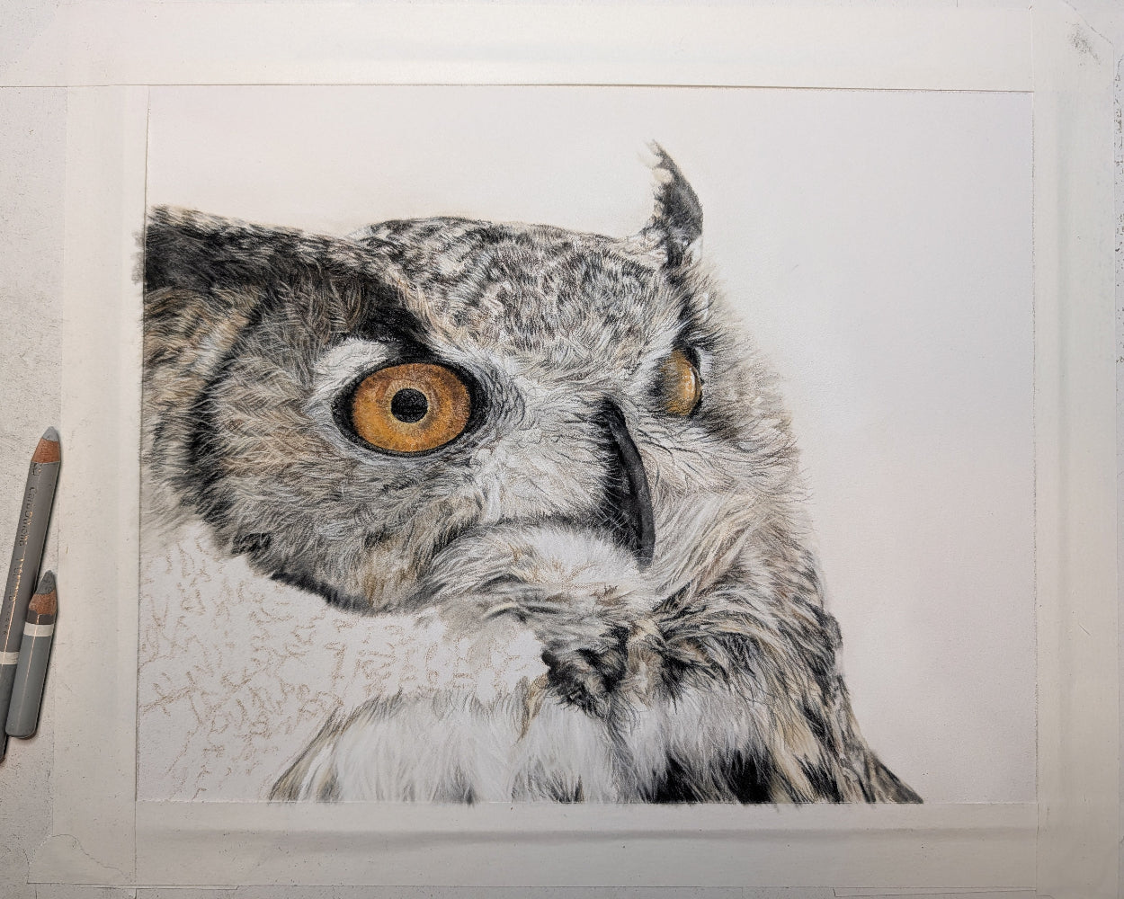 Detailed drawing of an owl on a textured surface with art supplies.