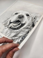 Hand holding a pastel sketch of a dog's face on a white background