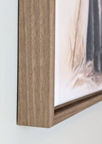 Close-up of a wooden picture frame with a blurred artwork background