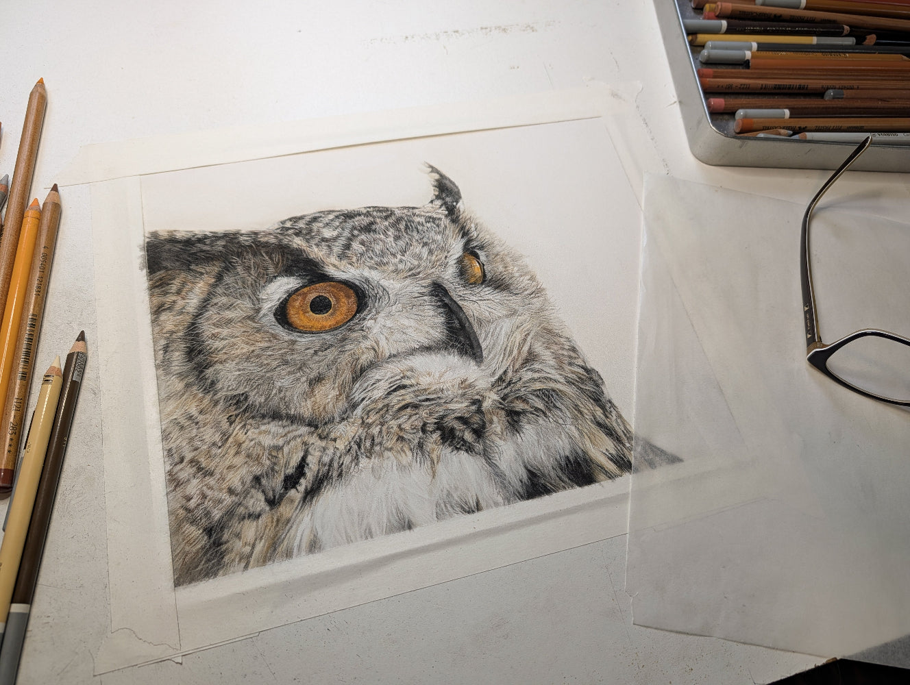 Detailed drawing of an owl on a white surface with art supplies.